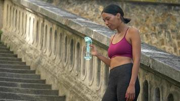 Eine Frau macht nach dem Training eine Pause, um Wasser zu trinken.