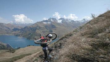Mountain biker carries his bike up the mountains trail. video