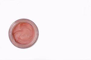 Red cosmetic clay in glass bottle, white background, isolated photo