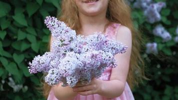 uma menina ao ar livre em um parque ou jardim segurando flores lilás arbustos lilases no parque de verão