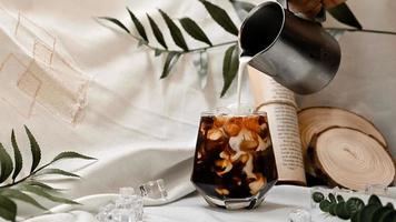 Barista pouring milk into a glass of iced coffee photo