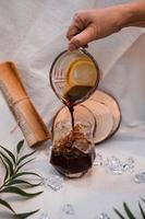 Barista pouring milk into a glass of iced coffee photo