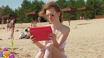 Mujer joven usa tableta de computadora en la orilla del río de la playa video