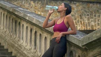 Eine Frau macht nach dem Training eine Pause, um Wasser zu trinken.