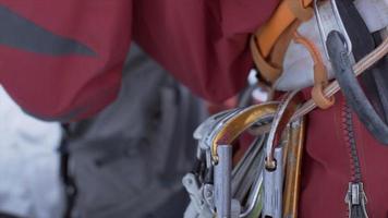 close-up de mosquetões em um cinto de arnês de escalada em um alpinista nas montanhas.