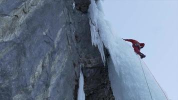 um homem escalando no gelo uma cachoeira congelada nas montanhas. video