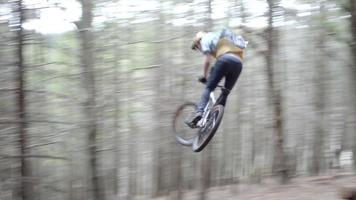 en man som hoppar sin mountainbike i en skog.