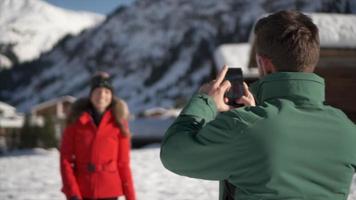 un uomo fotografa sua moglie, lo stile di vita sulla neve in una stazione sciistica. video
