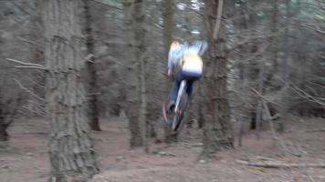 en man som hoppar sin mountainbike i en skog.