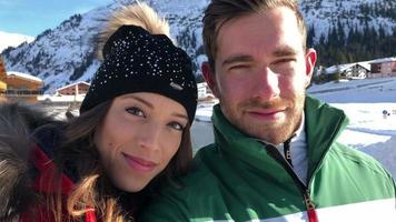 una coppia di uomini e donne scatta una fotografia selfie stile di vita sulla neve in una stazione sciistica. video