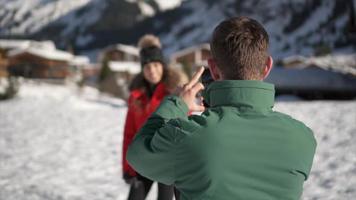 un uomo fotografa sua moglie, lo stile di vita sulla neve in una stazione sciistica. video
