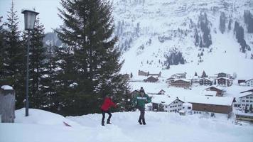 um casal de homem e mulher tendo um estilo de vida lúdico de luta de bola de neve na neve em uma estância de esqui. video