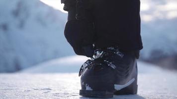 una donna con scarponi da sci che si prepara ad andare a sciare sulla neve in una stazione sciistica.