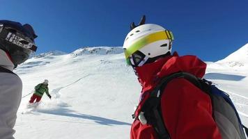 skiërs geven een high five feestgroet aan hun vriend na het skiën van een berg. video