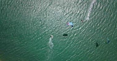 vista aerea del drone di un uomo che fa kitesurf su una tavola da aquilone in un lago lagunare.