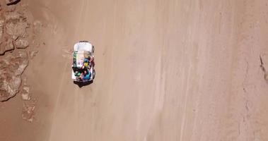 Vista aérea de un vehículo todoterreno 4x4 conduciendo en el viaje de surf en la playa. video