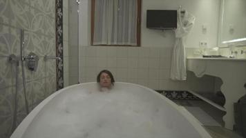 una mujer disfruta de un baño de burbujas en una bañera en un resort de lujo. video