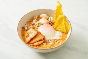 Rice vermicelli noodles with meatball, roasted pork and egg in spicy soup photo