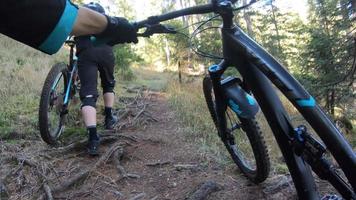 POV view of a mountain biker hands handlebars biking on a singletrack trail.