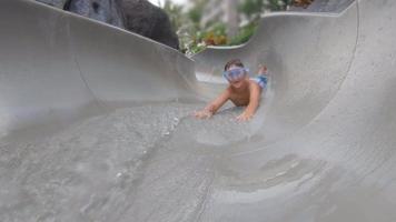 um menino brinca em um toboágua em uma piscina em um resort de hotel. video