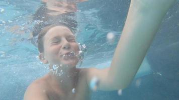 A boy plays and swims underwater in a pool at a hotel resort. video