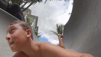 A boy plays on a waterslide water slide in a pool at a hotel resort.