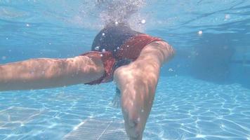 um menino brinca e nada debaixo d'água na piscina de um hotel resort. video