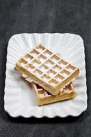 Belgium waffers with sugar powder on ceramic plateon black board background. photo