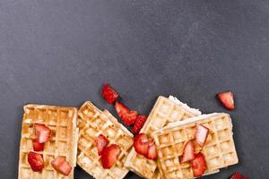Belgium waffers and strawberries on black board background. photo
