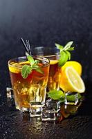 Two glasses with cold traditional iced tea with lemon, mint leaves and ice cubes. photo