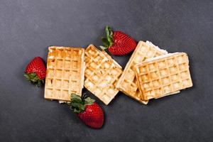 Belgium waffers and strawberries on black board background. photo