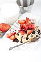 Belgium waffers with sugar powder, strawberries and chocolate on ceramic plate on white table. photo