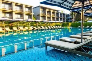 Umbrella and pool bed around outdoor swimming pool in hotel resort for travel holiday vacation photo