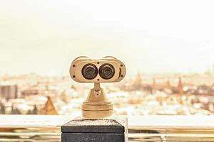 Coin-operated binoculars on the observation deck overlooking the city from a height at sunset. Winter, snowfall. photo