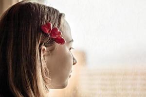 Portrait of a beautiful sad girl looking out the window with hope and expectation. Hairpin with hearts. First love on Valentine's Day photo
