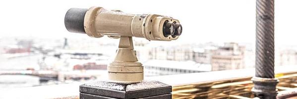 Coin-operated binoculars on the observation deck overlooking the city from above. Winter, snowfall. photo