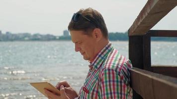 um homem na praia usando um tablet de computador video