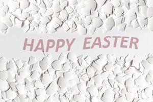Pieces of white eggshell of broken chicken egg isolated on white background. Easter background. Top view.English text Happy Easter photo