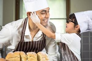 Asian Boy wear glasses Tease dad cooking with white flour Kneading bread dough teaches children practice baking ingredients bread, egg on tableware in kitchen lifestyle happy Learning life with family photo