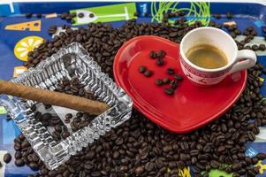 Composición de granos de café con taza y platillo en forma de corazón foto