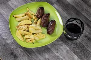 plate sausages potatoes and a glass of wine photo