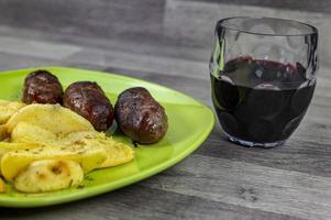 plate sausages potatoes and a glass of wine photo