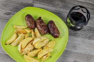 plate sausages potatoes and a glass of wine photo