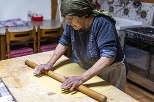 abuela extendiendo la masa recién amasada foto