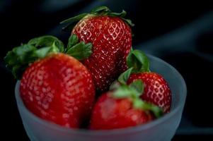 cup of ripe strawberries on black background photo