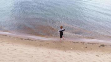 A young woman in a dress runs along the beach Aerial shoot video