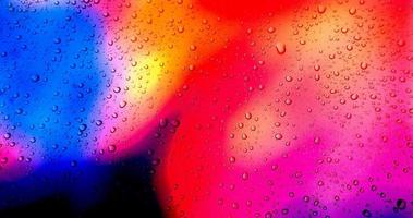 Rain drops on colorful glass window background photo