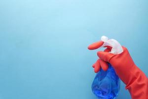 Mano en guantes de goma roja sosteniendo una botella de spray con espacio de copia foto