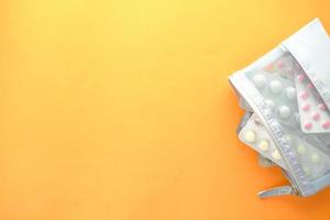 Top view pills of blister pack in a small bag on orange background photo