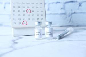 vacuna contra el coronavirus, jeringa y calendario en la mesa foto